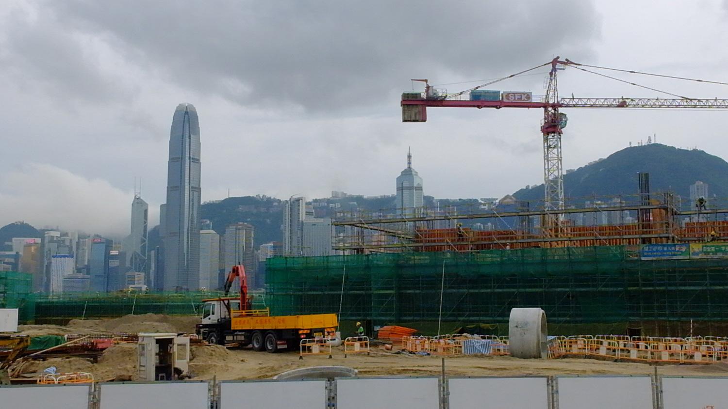 Urban construction site with cranes and Hong Kong skyline in the background
