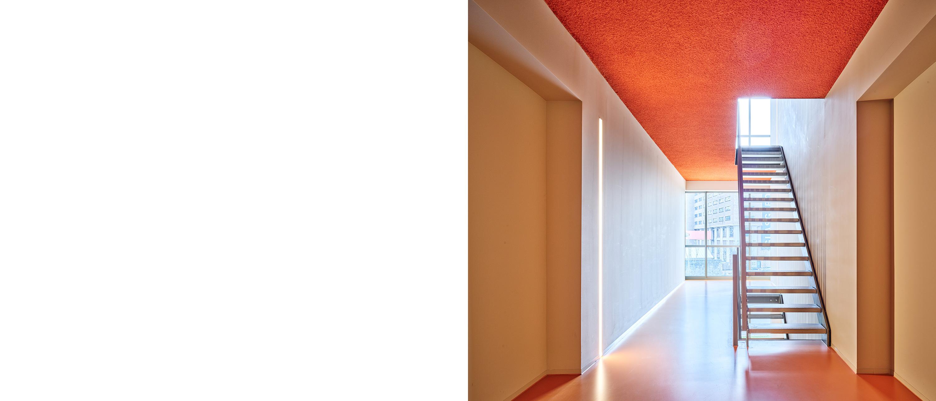 Modern hallway with red acoustic ceiling and natural light