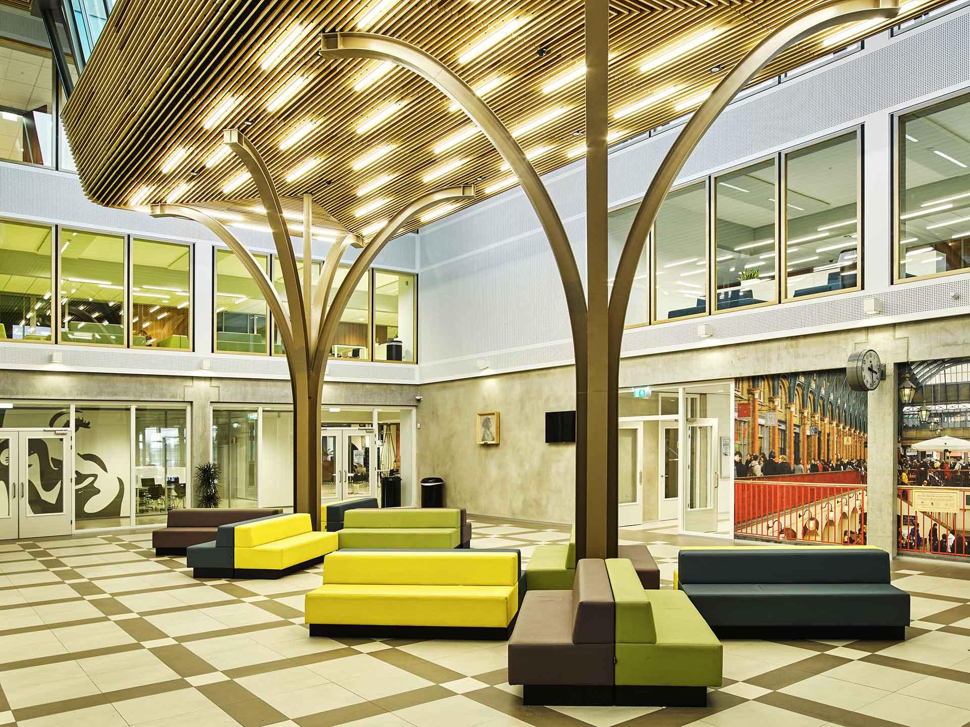 Modern atrium of Melanchthon school with tree-shaped acoustic ceiling and colorful seating